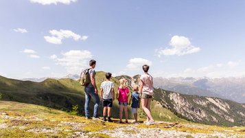 Familie in den Bergen macht eine Pause mit toller Aussicht in der Nähe des Familienhotels Almfamilyhotel Scherer in Tirol.