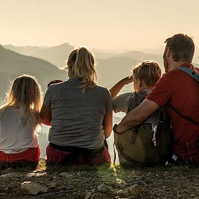 Familie in den Bergen macht eine Pause mit toller Aussicht in der Nähe des Familienhotels Almfamilyhotel Scherer in Tirol.