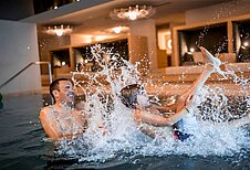 Vater und Sohn planschen gemeinsam im Indoor-Pool des Familienhotels Alpenhof Dolomit Family