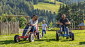 Salzburger Land im Sommer: Familie auf dem Go-Kart unterwegs auf einer Wiese in Mühlbach.