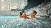 Eltern entspannen im hoteleigenen Wellnessbereich im warmen Indoor-Pool im Familienhotel Alpenhotel Kindl in Tirol.