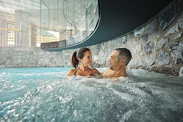 Eltern entspannen im hoteleigenen Wellnessbereich im warmen Indoor-Pool im Familienhotel Alpenhotel Kindl in Tirol.