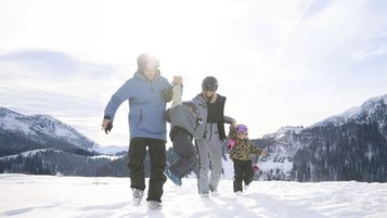 Gäste des Familienhotels Das Bayrischzell in Bayern sind mit ihren Kinder am Sudelfeld Skifahren.