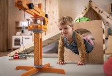 Kleiner Junge krabbelt durch ein Holzspielgerät im Spielzimmer des Familienhotels Elldus im Erzgebirge.