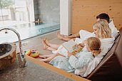Dreiköpfige Familie entspannt im Bademantel im Familien-Wellnessbereich im Habachklause Familien Bauernhof Resort im Salzburger Land.