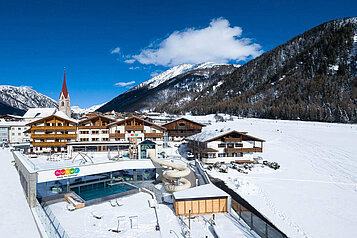 Das Familienhotel Huber in Südtirol umgeben von einer winterlichen Berglandschaft und großzügigen Außenanlage mit viel Platz zum Spielen für Kinder.