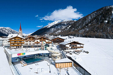 Das Familienhotel Huber in Südtirol umgeben von einer winterlichen Berglandschaft und großzügigen Außenanlage mit viel Platz zum Spielen für Kinder.