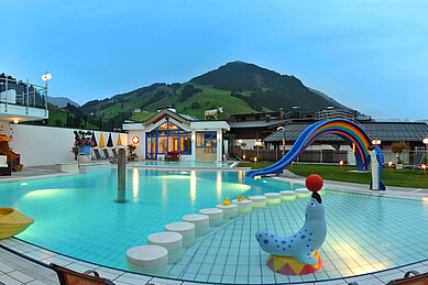 Pool mit Kinderrutsche und anderen Spielmöglichkeiten mit Ausblick auf die Berge im Wellness- & Familienhotel Egger in Saalbach Hinterglemm.