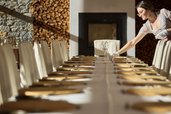 Mitarbeiterin deckt einen festlich vorbereiteten Tisch im Restaurant des Familienhotel Bella Vista Südtirol.