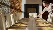 Mitarbeiterin deckt einen festlich vorbereiteten Tisch im Restaurant des Familienhotel Bella Vista Südtirol.