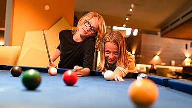 Zwei Teenager spielen zusammen im Familienhotel Billard.