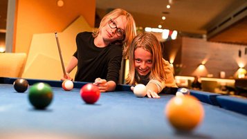 Zwei Teenager spielen zusammen im Familienhotel Billard.