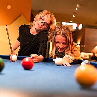 Zwei Teenager spielen zusammen im Familienhotel Billard.