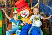 Zwei Kinder haben Spaß in der Softplayanlage mit Maskottchen Happy im Familienhotel Alphotel Tyrol in Südtirol.