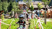 Kinder fahren auf dem Außengelände des Galtenberg Family & Wellness Resorts durch den Bikepark.