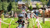 Kinder fahren auf dem Außengelände des Galtenberg Family & Wellness Resorts durch den Bikepark.