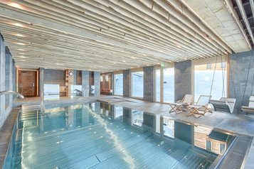 Innenpool mit Liegen und großem Fensterbereich im Familienhotel Gorfion in Liechtenstein.