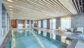 Innenpool mit Liegen und großem Fensterbereich im Familienhotel Gorfion in Liechtenstein.
