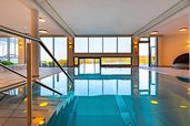 Moderner Indoor-Pool im Familienhotel Petschnighof mit großen Panoramafenstern und Blick in die Natur.