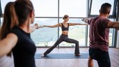 Gäste nehmen an einer Yogastunde mit Panoramablick im Familien Resort Petschnighof in Kärnten teil.
