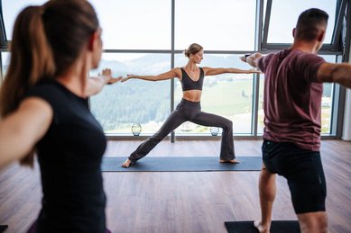 Gäste nehmen an einer Yogastunde mit Panoramablick im Familien Resort Petschnighof in Kärnten teil.