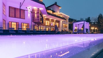 Poollandschaft am Abend mit Ambientebeleuchtung im Familienhotel Engel Gourmet & Spa in Südtirol.