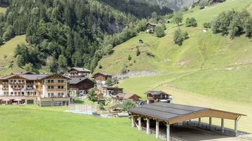 Sonnige Terrasse des Familienhotels Oberkarteis mit modernen Sitzbereichen und Blick auf die umliegenden Berge im Salzburger Land.