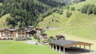 Sonnige Terrasse des Familienhotels Oberkarteis mit modernen Sitzbereichen und Blick auf die umliegenden Berge im Salzburger Land.
