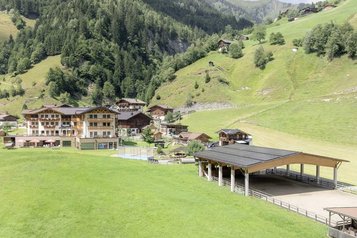Sonnige Terrasse des Familienhotels Oberkarteis mit modernen Sitzbereichen und Blick auf die umliegenden Berge im Salzburger Land.