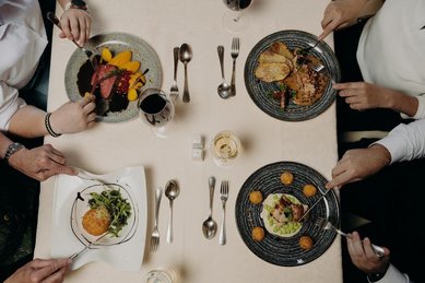 Eine Familie genießt gemeinsam ein Essen am gedeckten Tisch im Restaurant des Hotel Sonngastein im Salzburger Land.
