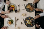 Eine Familie genießt gemeinsam ein Essen am gedeckten Tisch im Restaurant des Hotel Sonngastein im Salzburger Land.