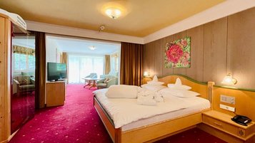 Der Wohnraum im Familienzimmer mit gemütlicher Couch und einem Fernseher im Wellness- & Familienhotel Egger in Saalbach Hinterglemm.