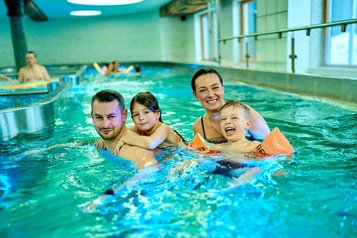 Familie mit zwei Kindern beim fröhlichen Badespaß im Hallenbad des Familienhotels Feldberger Hof im Schwarzwald.