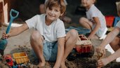 Kinder spielen im Sandbereich des Familienhotels Oberkarteis im Salzburger Land mit Schaufel und Spielzeug.