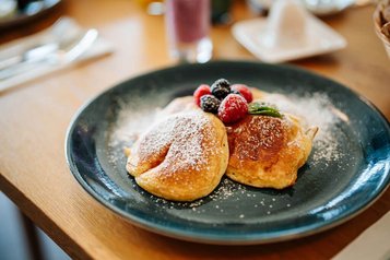 Frisch zubereitete Pancakes mit Beeren und Puderzucker im Familien Resort Petschnighof in Kärnten.