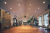 Der Fitnessraum mit Tageslicht und vielen Gerätschaften im Familienhotel Post Family Resort im Salzburger Land.