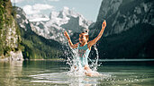 Oberösterreich im Sommer: In Dachstein Salzkammergut könnt ihr im Grosausee euch abkühlen. Kind plantscht glücklich im Wasser.