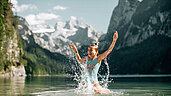 Oberösterreich im Sommer: In Dachstein Salzkammergut könnt ihr im Grosausee euch abkühlen. Kind plantscht glücklich im Wasser.