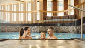 Eltern planschen mit ihrem Kind im Indoor-Pool im Alpenhotel Kindl
