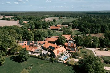 Luftaufnahme des weitläufigen Hotelgeländes vom Familienhotel Landhaus Averbeck, eingebettet in die grüne Landschaft der Lüneburger Heide.