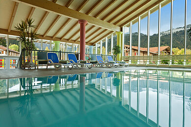 Schwimmbad mit Liegen und Panoramafenstern im Familienhotel Spa- & Familien-Resort Krone in den Allgäuer Alpen.