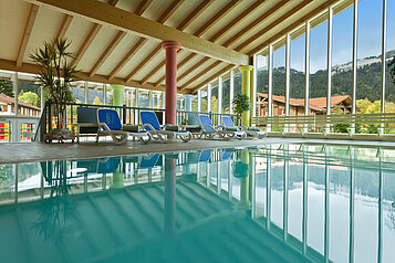 Schwimmbad mit Liegen und Panoramafenstern im Familienhotel Spa- & Familien-Resort Krone im Allgäu.