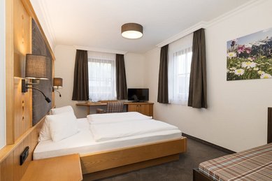 Helles Familienzimmer im Familienhotel Oberkarteis mit gemütlichem Doppelbett, Schreibtisch und modernem Landhausstil.