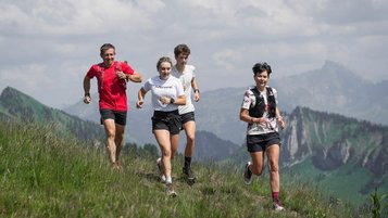 Vier sportliche Gäste joggen über einen Bergpfad mit Alpenpanorama beim Familienhotel Sonne Bezau.