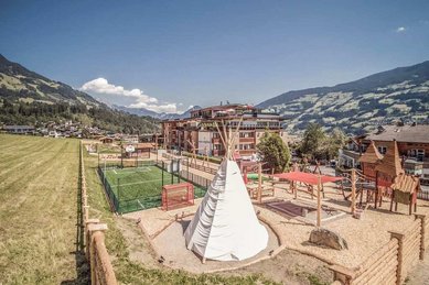Großer Außenspielplatz beim Familienhotel Mia Alpina in Tirol mit Tipi, Spielgeräten und Bergpanorama.