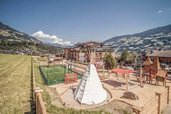 Großer Außenspielplatz beim Familienhotel Mia Alpina in Tirol mit Tipi, Spielgeräten und Bergpanorama.