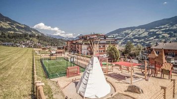 Großer Außenspielplatz beim Familienhotel Mia Alpina in Tirol mit Tipi, Spielgeräten und Bergpanorama.