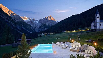 Außenansicht Pool, mit Abendbeleuchtung im Sommer im Familienhotel Bella Vista in Südtirol.