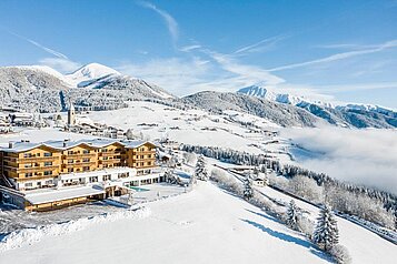 Luftaufnahme des Familienhotels Family Home Alpenhof im Winter.