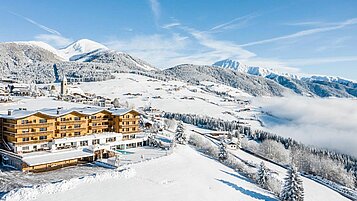 Luftaufnahme des Familienhotels Family Home Alpenhof im Winter.